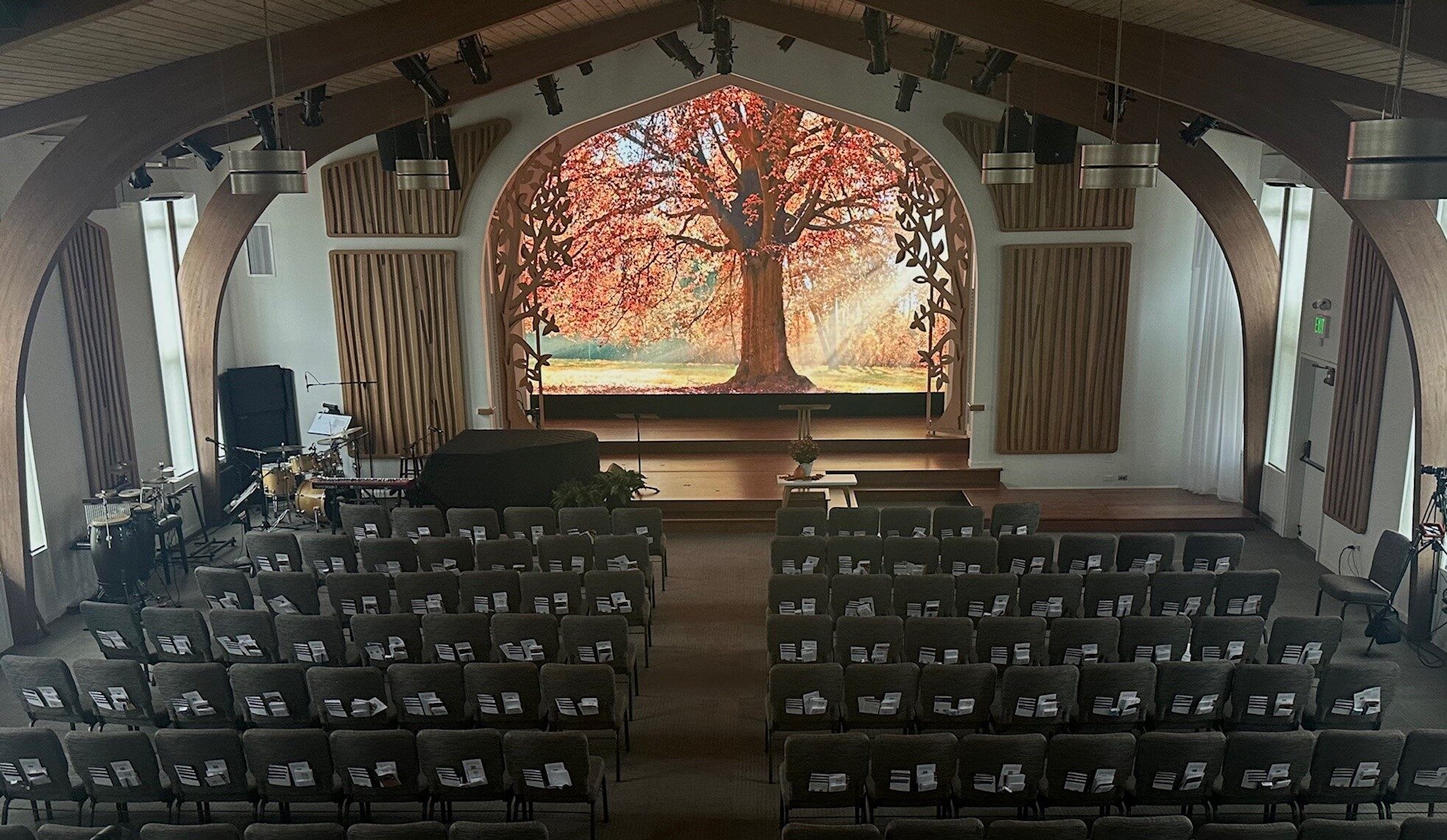 A large screen showing a vibrant autumn tree serves as a focal point for the wide room, with dark wood arches framing it.